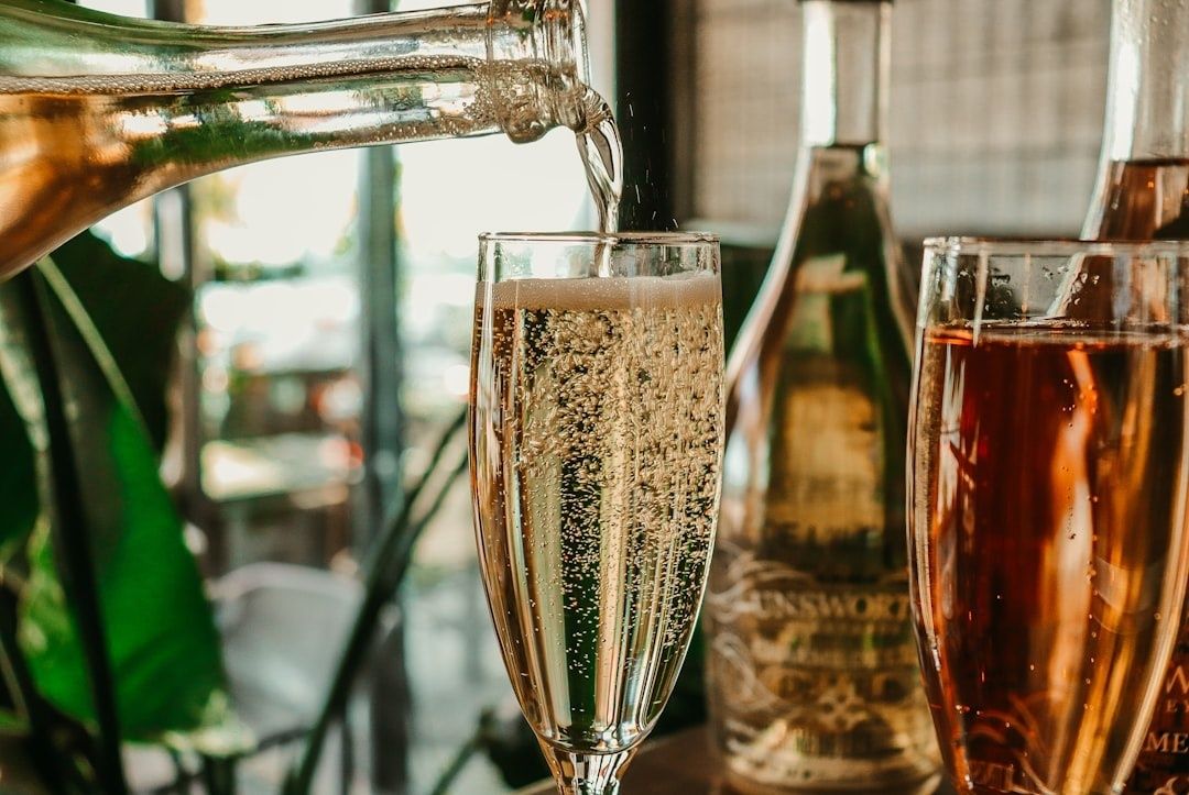 Sparkling wine poured into a flute beside other tasting glasses