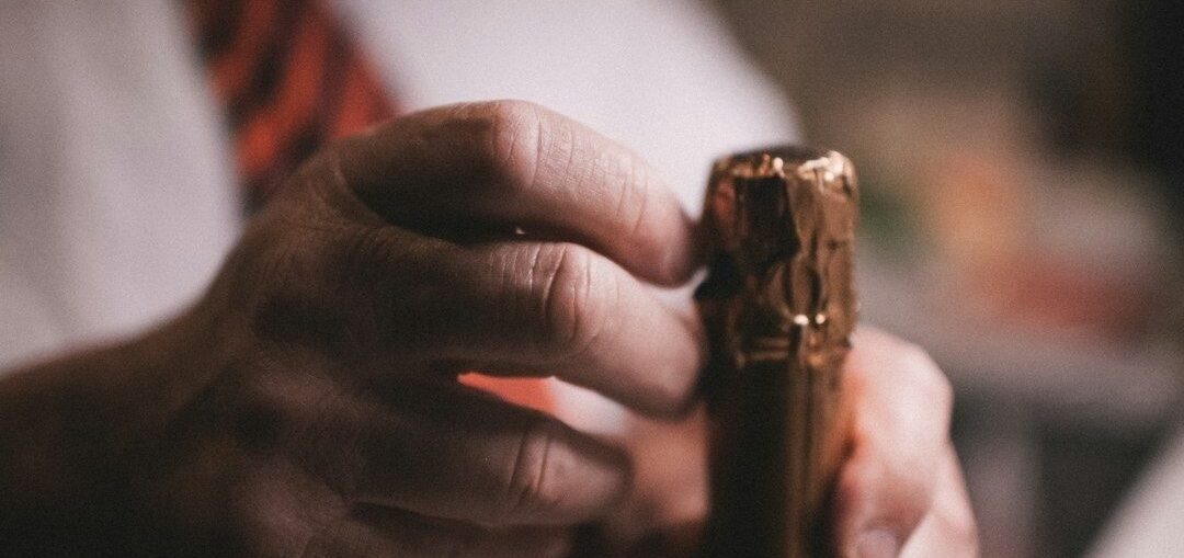Close-up of hands holding a partially opened wine bottle cork