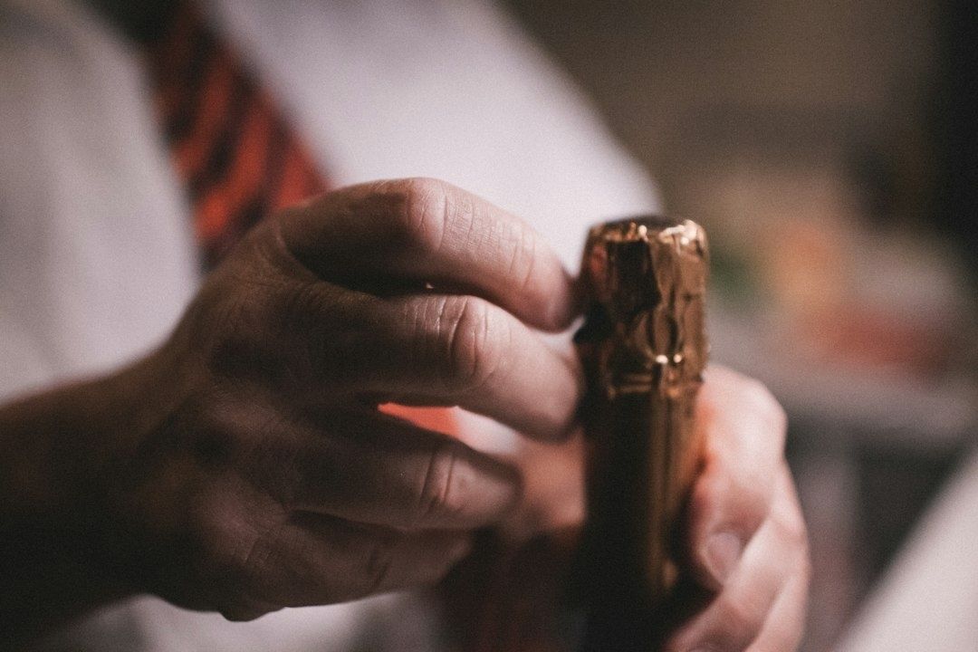 Close-up of hands holding a partially opened wine bottle cork