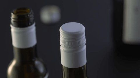 Close-up of wine bottles showing screwcaps and an open neck